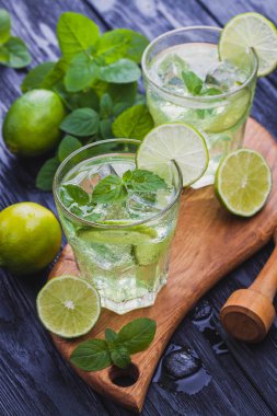 Siyah ahşap bir masa üzerinde buz ile soğuk mojito serinletici iki bardak