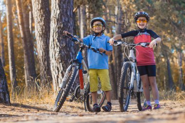 çocuklar açık havada kask içinde Bisiklete binme güneşli forest.happy çocuklarda abicycles