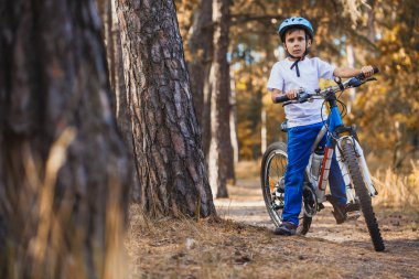Güneşli ormandaki bir bisikletle komik çocuk. mutlu çocuk açık havada kask içinde Bisiklete binme