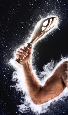 Elini mavi bir yangında gold Kupası karanlık bir arka plan üzerinde tutuyor. Bir yarışmada kazanan.