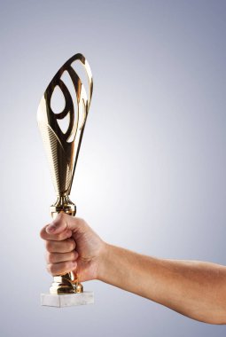 Elini mavi bir yangında gold Kupası karanlık bir arka plan üzerinde tutuyor. Bir yarışmada kazanan.