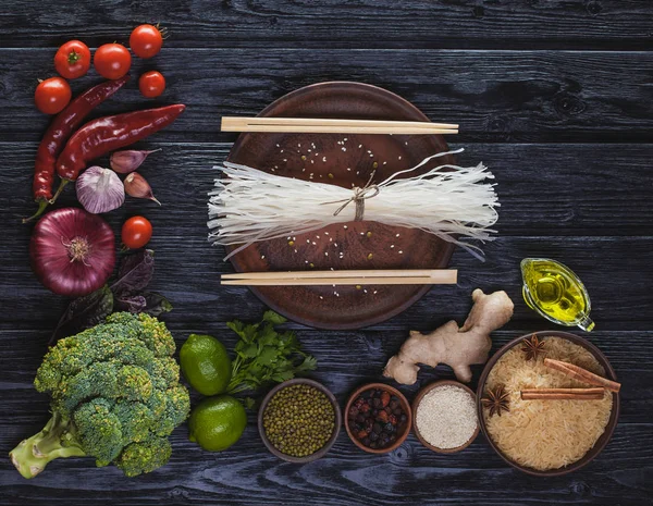 黒の木製テーブルの上の米麺からオリエンタル料理の原料 — ストック写真