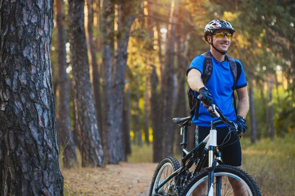 Happy man cyclist rides in the forest on a mountain bike. Adventure travel.