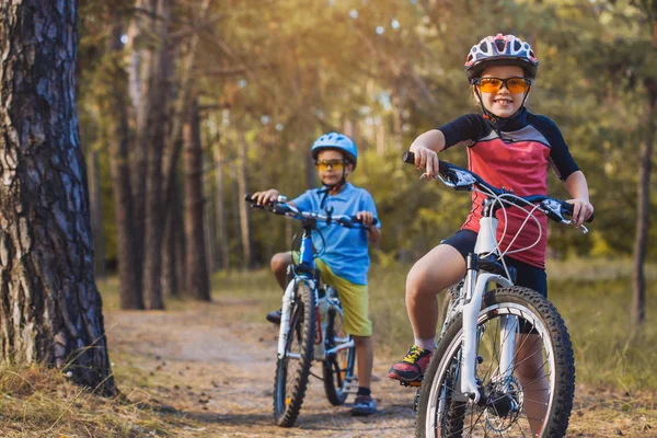 çocuklar açık havada kask içinde Bisiklete binme güneşli forest.happy çocuklarda abicycles