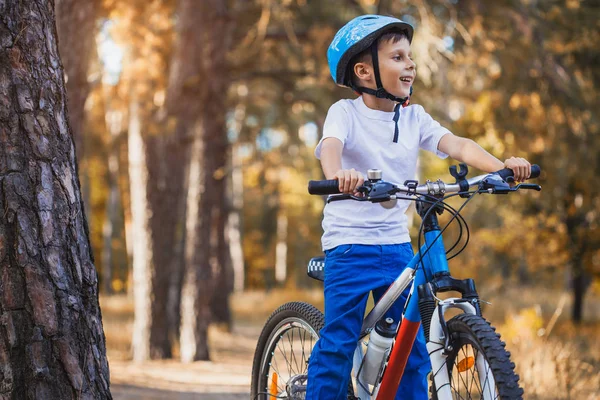 有趣的孩子骑自行车在阳光明媚的森林 快乐的男孩骑头盔在户外骑自行车 — 图库照片