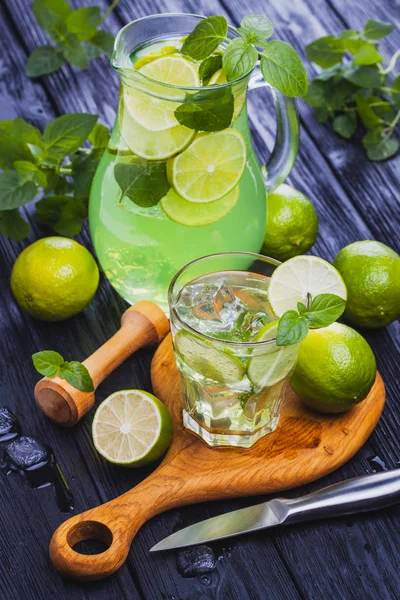 Cold refreshing summer lemonade mojito in a glass on a black wooden background