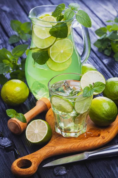 Cold refreshing summer lemonade mojito in a glass on a black wooden background