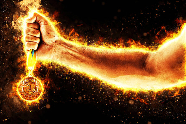 Man's hand in a fire is holding up gold medal on a dark background. Winner in a competition.
