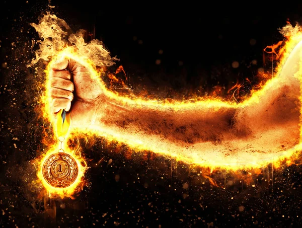 Man\'s hand in a fire is holding up gold medal on a dark background. Winner in a competition.