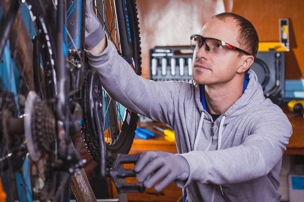 handsome bicycle mechanic doing his professional work in workshop.