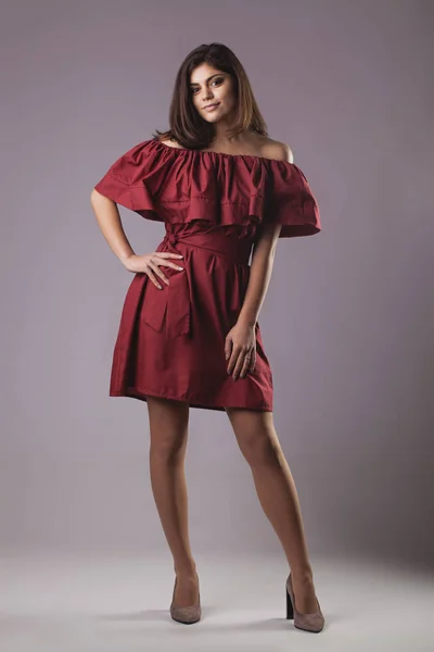 Μελαχρινή Νεαρή Γυναίκα Κόκκινο Φόρεμα Που Παρουσιάζουν Γκρίζο Φόντο — Φωτογραφία Αρχείου