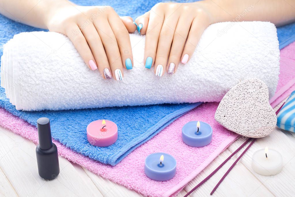 beautiful colored manicure with decor, orchid, towel and candle on the white wooden table. spa