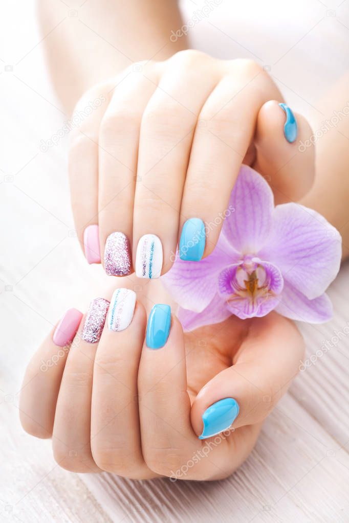 beautiful colored manicure with decor, orchid, towel and candle on the white wooden table. spa