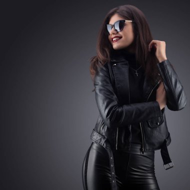 Esmer kız siyah deri ceketli. Güzel model gri bir arka plan üzerinde. Stüdyo photosession