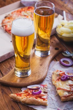 iki bardak sıcak pizza eski ahşap masa ile hafif bira. Önemli bir akşam yemeği