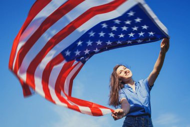 Ulusal Amerikan bayrağı mavi gökyüzü ile mutlu gülümseyen genç kadın. Bağımsızlık günü, 4 Temmuz