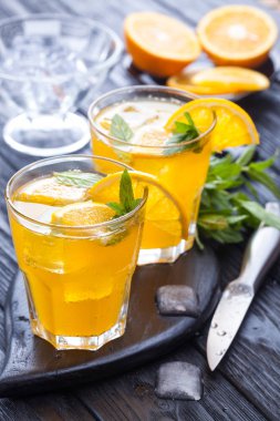 Turuncu buz ve siyah ahşap bir masa üzerinde taze nane kokteyli. canlandırıcı yaz içeceği