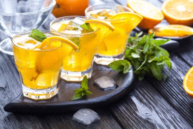 Turuncu buz ve siyah ahşap bir masa üzerinde taze nane kokteyli. canlandırıcı yaz içeceği