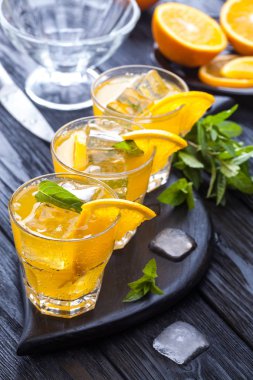 Turuncu buz ve siyah ahşap bir masa üzerinde taze nane kokteyli. canlandırıcı yaz içeceği