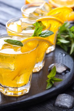 Turuncu buz ve siyah ahşap bir masa üzerinde taze nane kokteyli. canlandırıcı yaz içeceği