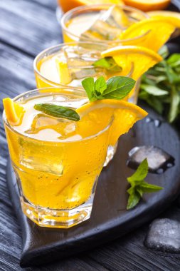 Turuncu buz ve siyah ahşap bir masa üzerinde taze nane kokteyli. canlandırıcı yaz içeceği