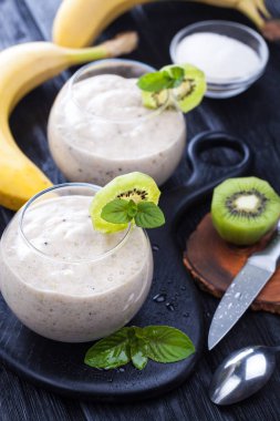 elma, kivi ve siyah ahşap bir masa üzerine nane taze muz smoothie. lezzetli ve sağlıklı bir kahvaltı