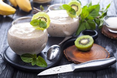 elma, kivi ve siyah ahşap bir masa üzerine nane taze muz smoothie. lezzetli ve sağlıklı bir kahvaltı