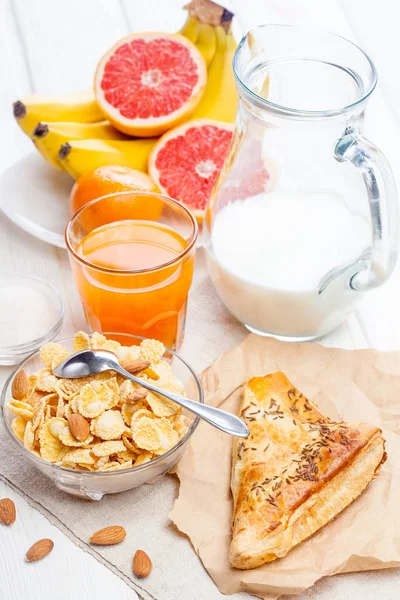 白の木製テーブルの上の健康的な朝食 コーンフレーク フルーツ フレッシュ ジュース 牛乳のボウル — ストック写真