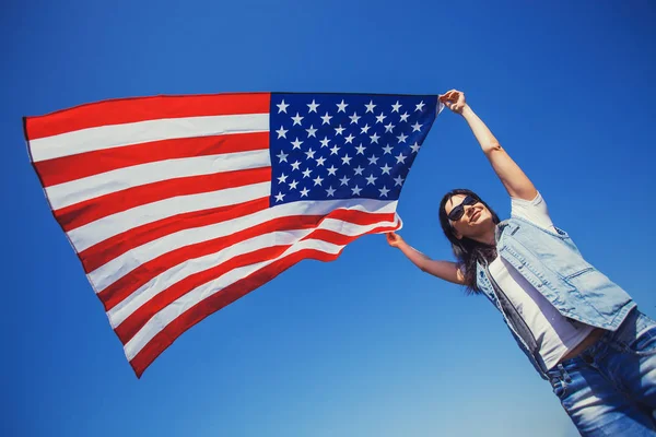 青空にアメリカ国旗を持つ若い女性の笑顔は幸せ 日独立記念日 — ストック写真