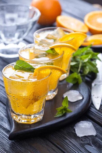 Orangencocktail Mit Eis Und Frischer Minze Auf Einem Schwarzen Holztisch — Stockfoto