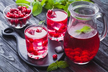 Kırmızı kiraz kokteyl buz ve siyah ahşap bir masa üzerinde taze nane. canlandırıcı yaz içeceği