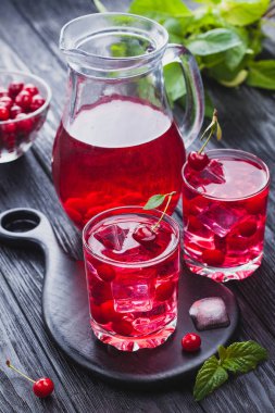 Kırmızı kiraz kokteyl buz ve siyah ahşap bir masa üzerinde taze nane. canlandırıcı yaz içeceği