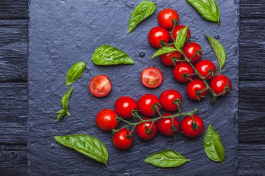 Bir siyah taze kiraz domates fesleğen ile yönetim kurulu arka plan kayrak. Kopya alanı ile Üstten Görünüm.