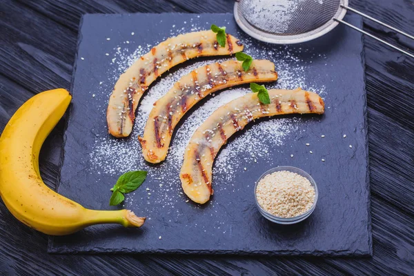 Sweet fried banana served on a black slate board. Healthy low-calorie dessert