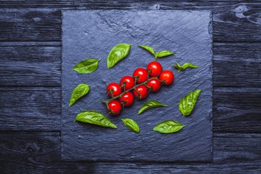 Bir siyah taze kiraz domates fesleğen ile yönetim kurulu arka plan kayrak. Kopya alanı ile Üstten Görünüm.