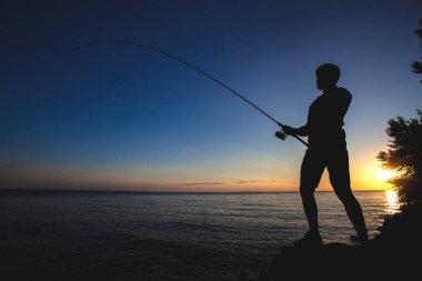 bir balıkçı batan güneşin arka plan üzerinde silüeti