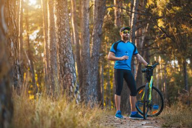Mutlu sakallı adam dağ bisikletiyle güneşli ormanda bisiklet sürüyor. Macera seyahati.