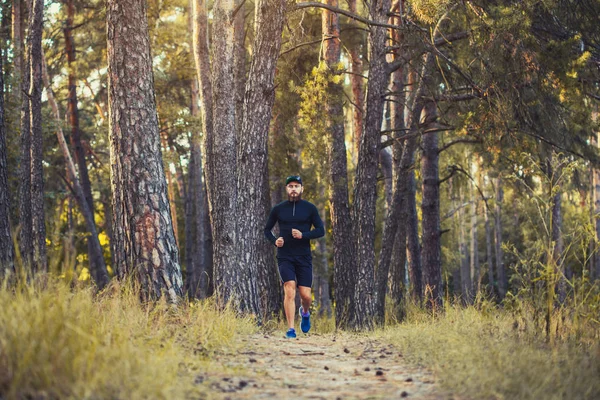 A bearded athlete runs along a picturesque forest path. healthy lifestyle concept