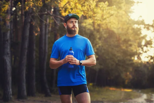 A bearded athlete prepares for a morning run along a picturesque forest path. healthy lifestyle concept