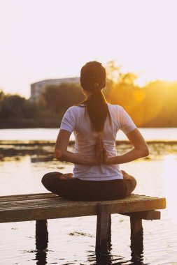 Gün batımında sahilde Yoga uygulamak genç esmer kadın