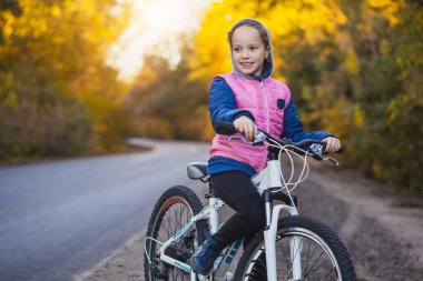 güneşli sonbahar ormandaki bir bisikletle evlat. mutlu kız açık havada Bisiklete binme