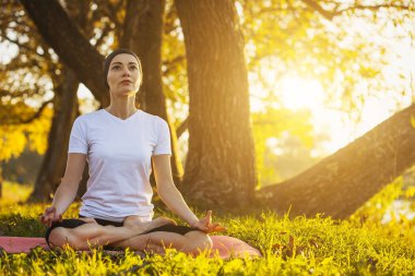 Gün batımında sonbahar parkta meditasyon güzel genç kız