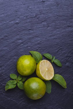 Olgun taze limes siyah arduvaz taş zemin üzerine nane ile. Kopya alanı ile Üstten Görünüm