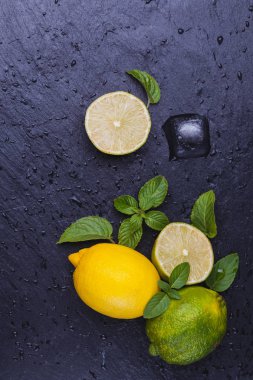 Buz, olgun taze limes siyah arduvaz taş zemin üzerine nane. Kopya alanı ile Üstten Görünüm