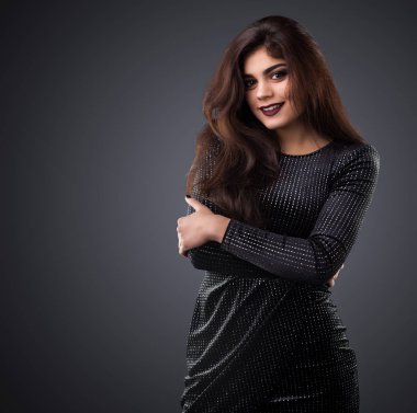 Gri arka plan üzerinde poz siyah elbiseli genç esmer kadın