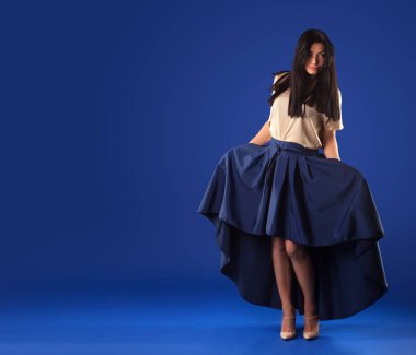 Bir mavi stüdyo arka plan üzerinde poz yemyeşil uzun etekli güzel esmer kadın