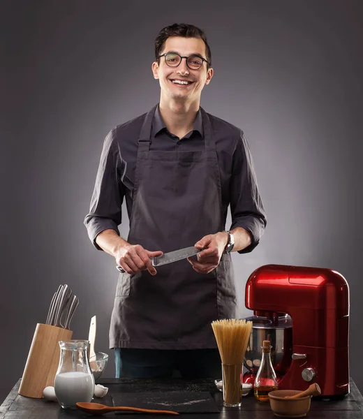 Handsome man prepares a delicious dish on a gray background. Studio photo