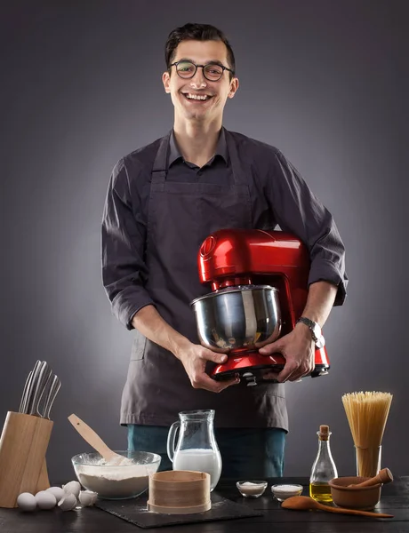 Man holding red food processor on a gray background. Studio photo