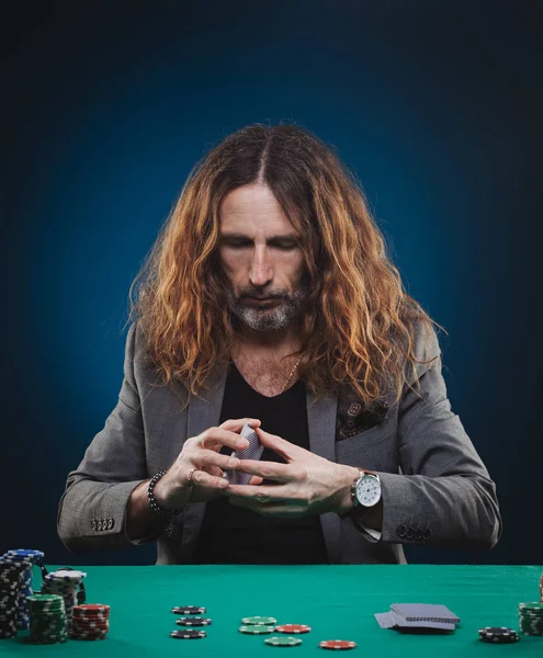 Bello dai capelli lunghi che gioca a poker in un casinò . — Foto Stock