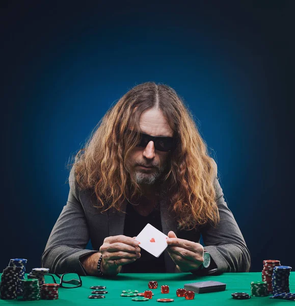 Bello dai capelli lunghi che gioca a poker in un casinò . — Foto Stock